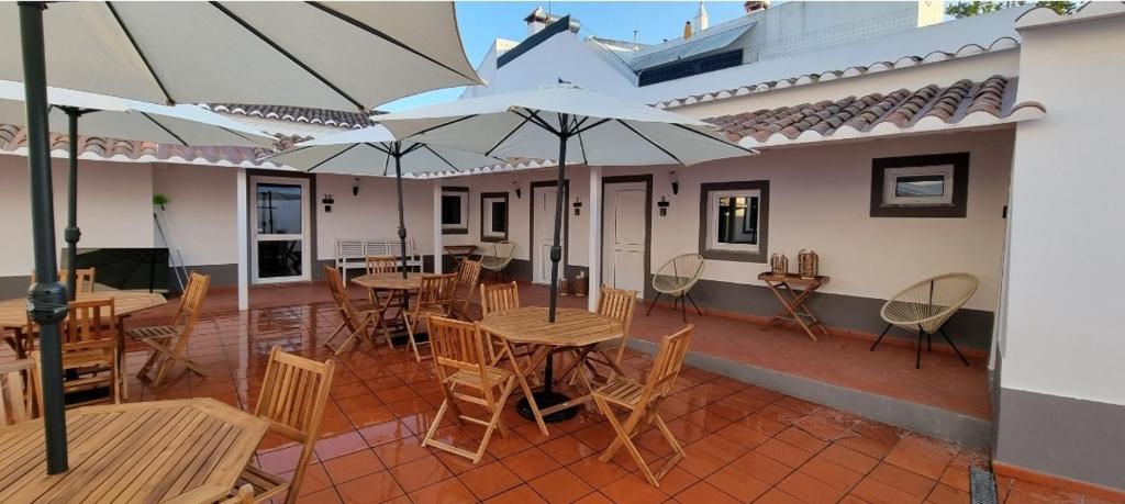 een patio met tafels, stoelen en parasols bij Casa Al'entejo in Ferreira do Alentejo