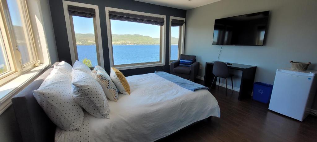 een slaapkamer met een bed en uitzicht op het water bij Coastal Lookout Suites in Corner Brook