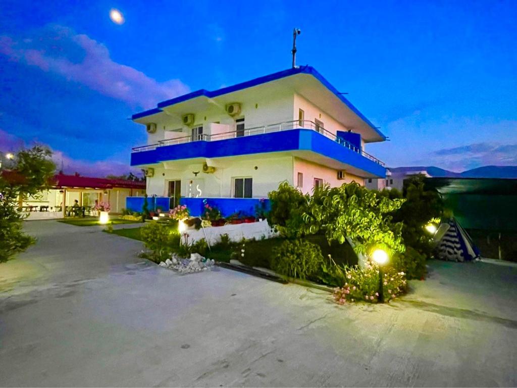 a large white house with a blue roof at night at KRED HOTEL in Orikum