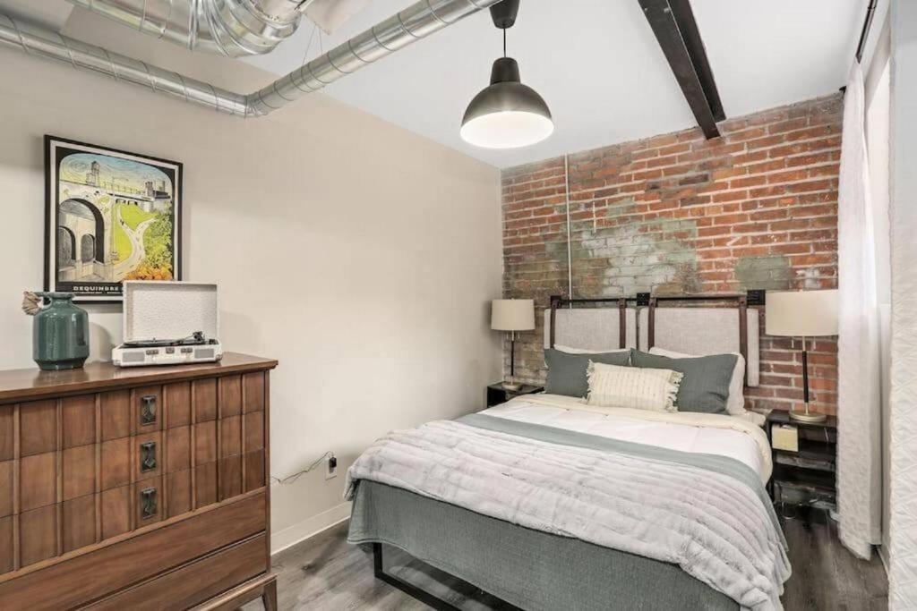 a bedroom with a bed and a brick wall at Luxury Downtown Loft Studio Fifty Nine 18 Pets in Detroit