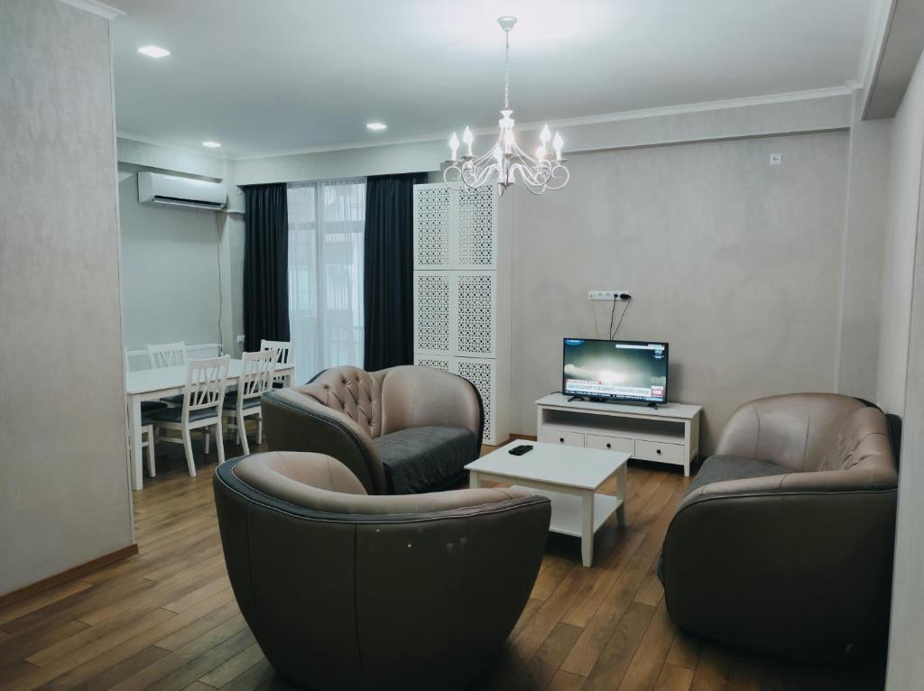 d'un salon avec des chaises et une télévision à écran plat. dans l'établissement City Luxury Apartment ll, à Tbilissi