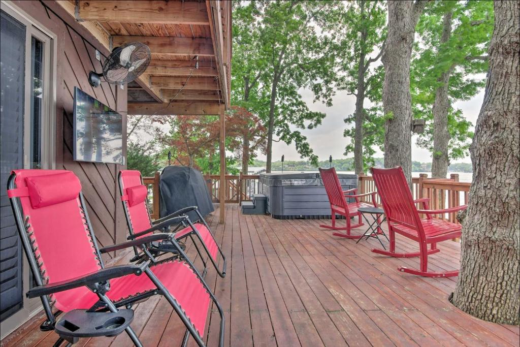 a deck with red chairs and a grill on a house at Waterfront Lake Ozark Home with Private Dock! in Lake Ozark