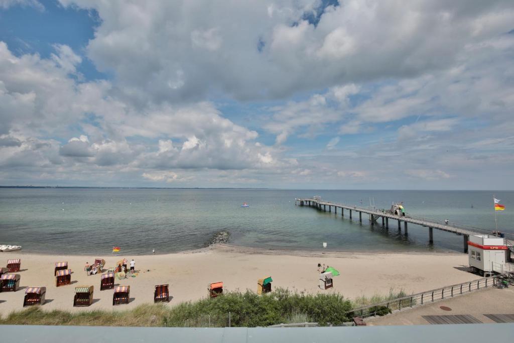 eine Gruppe von Menschen an einem Strand neben einem Pier in der Unterkunft Strandperle Ostsee Suite 1 in Niendorf