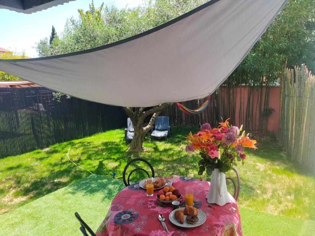 una mesa con un jarrón de flores y fruta. en Villa Carémeau 1 en Nimes