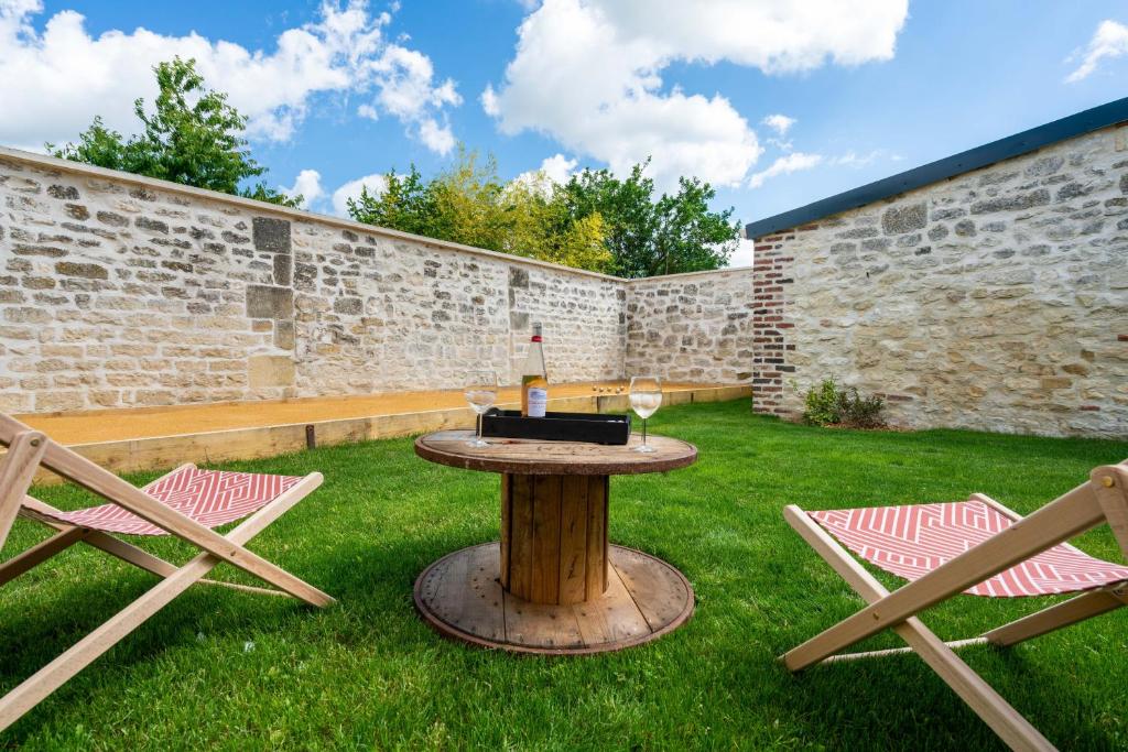 eine Terrasse mit einem Tisch mit einer Flasche Wein und 2 Stühlen in der Unterkunft Au Café des Souvenirs 