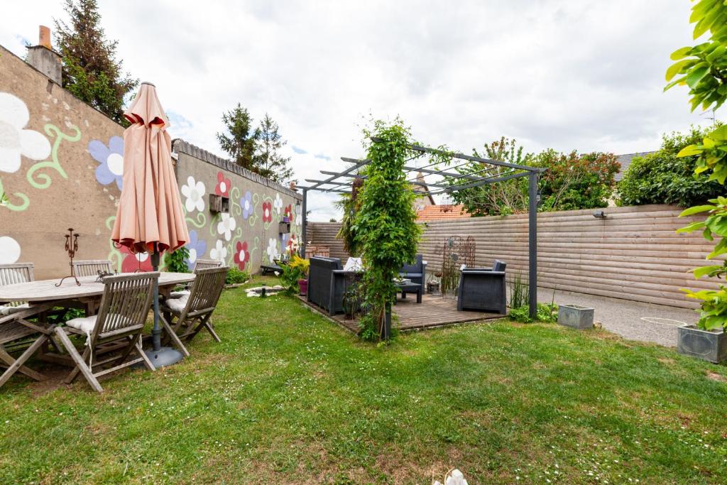 un patio trasero con una mesa y una sombrilla en Le Rethel, en Caen