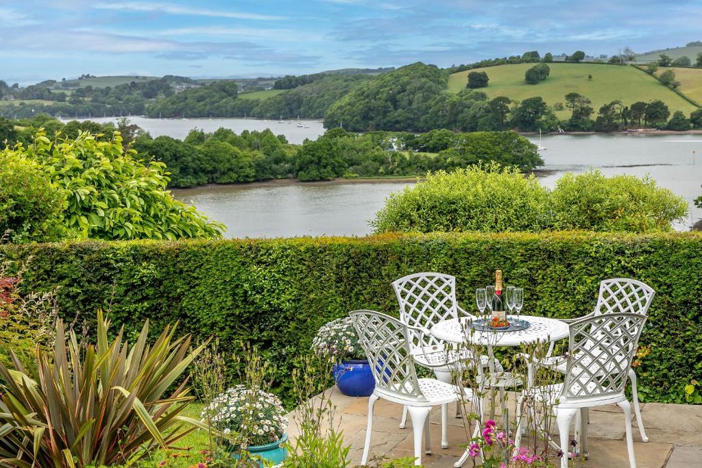 een tafel en stoelen met uitzicht op een rivier bij Curlew Cottage - Character Cottage with Superb River Views in Dittisham