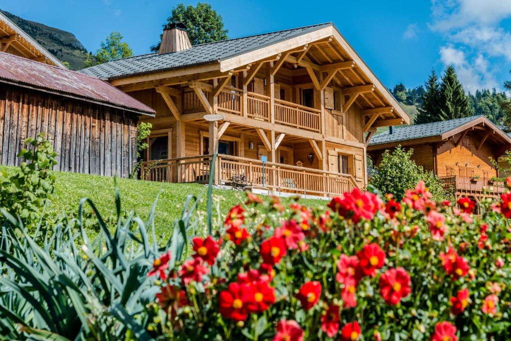 a wooden house with red flowers in front of it at Chalet La Canopée in La Giettaz