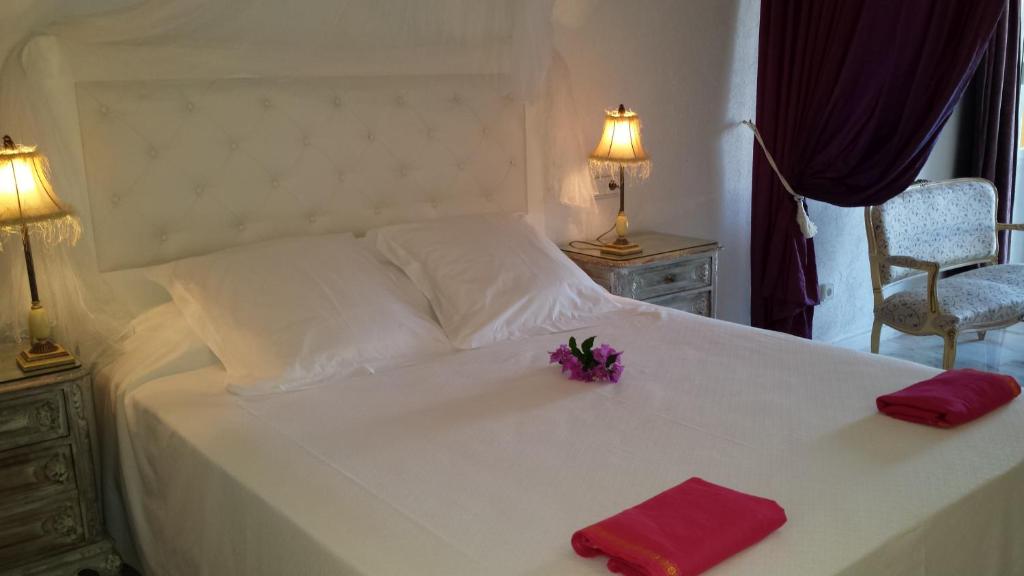 a white bed with two red napkins and flowers on it at Hotel Rural Can Maries in Puerto de San Miguel