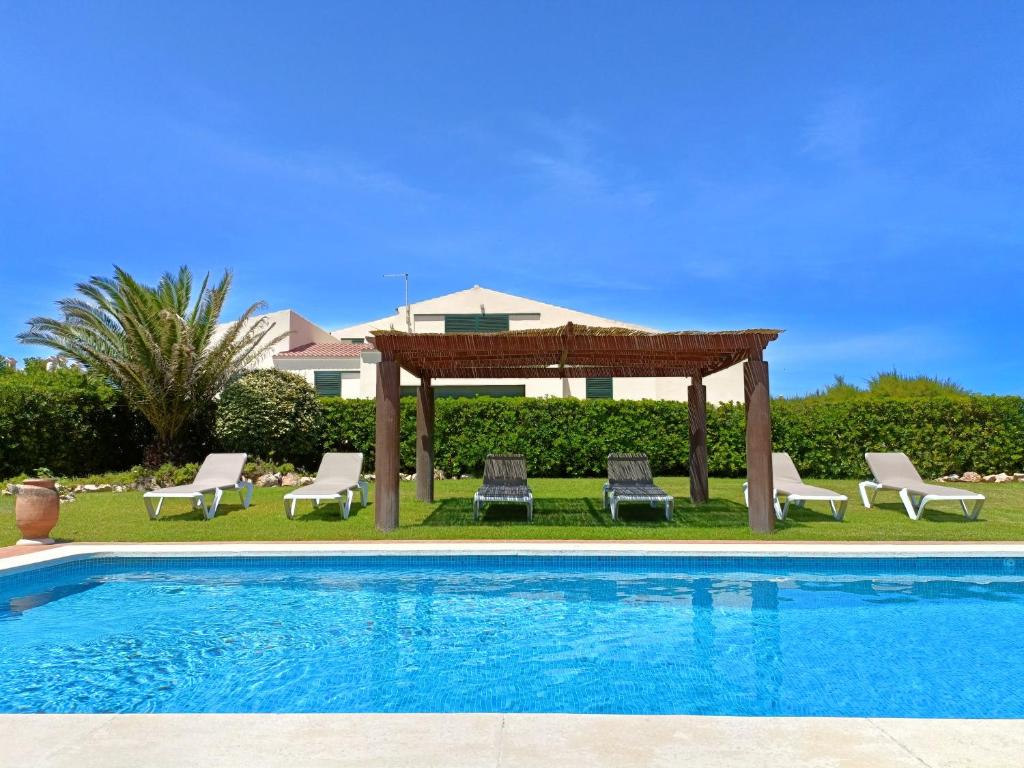 a swimming pool with a gazebo and chairs next to at VILLA VEGA RELAX EN EL PARAISO in Es Mercadal