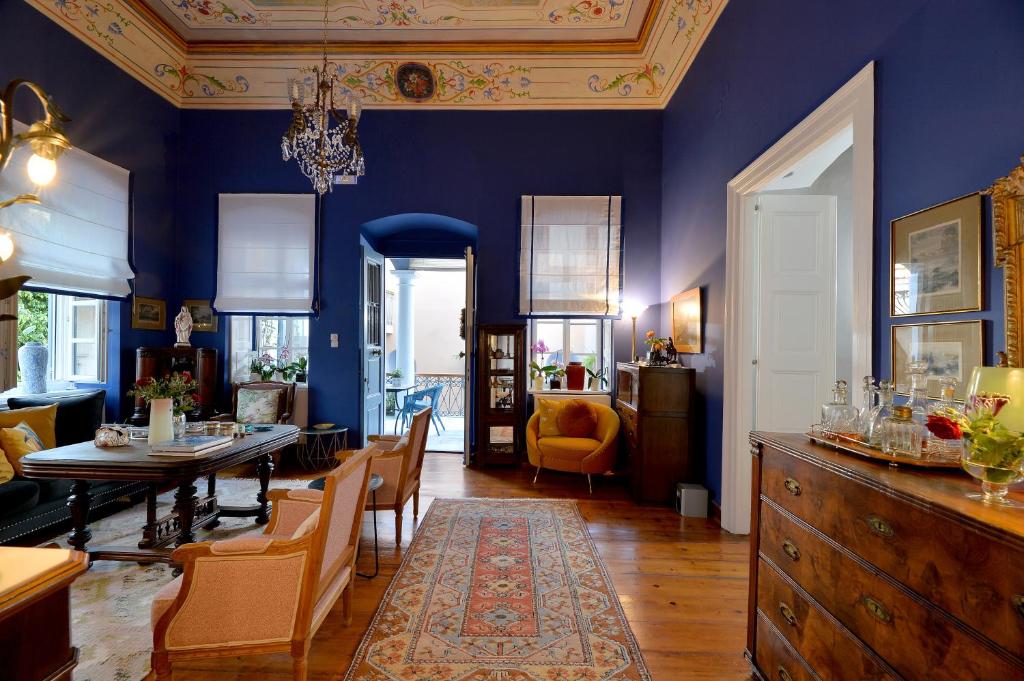 a living room with blue walls and a table and chairs at Arhontiko Ermoupolis in Ermoupoli