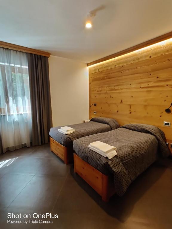 two beds in a room with a wooden wall at Chalet allemand in Sauze dʼOulx