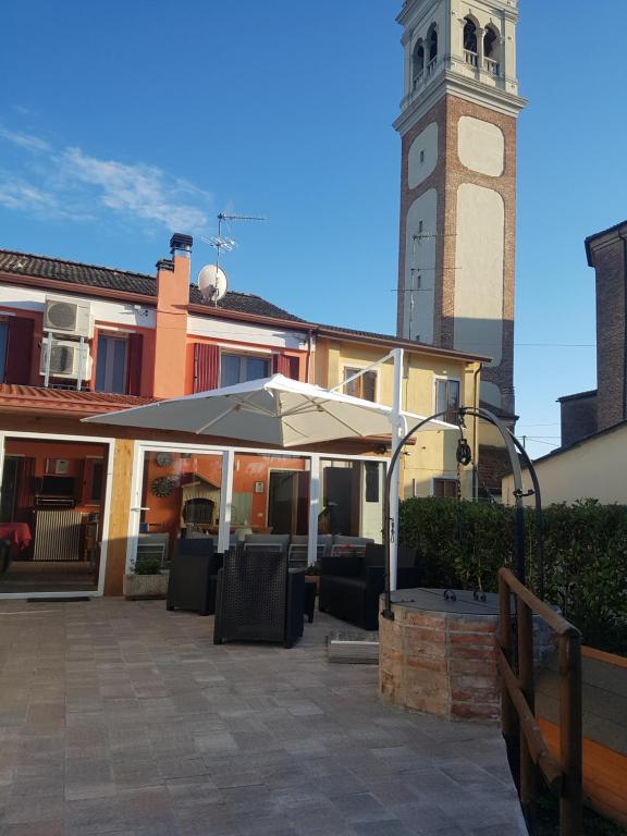 patio z parasolem i wieżą zegarową w obiekcie ALL'ANTICO CAMPANILE w mieście Rovigo