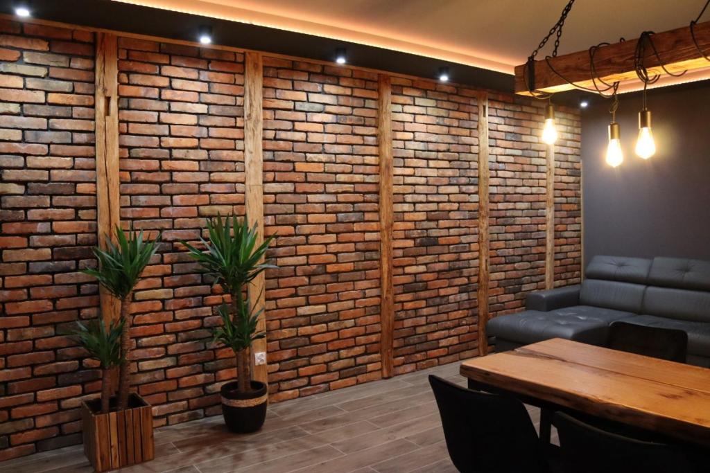 a room with a brick wall with a table and a couch at MERLIN Apartments in Zamość