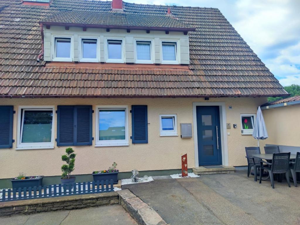 ein Haus mit blauen Fensterläden und einer Terrasse in der Unterkunft Ferienwohnung im Manbach in Freudenstadt