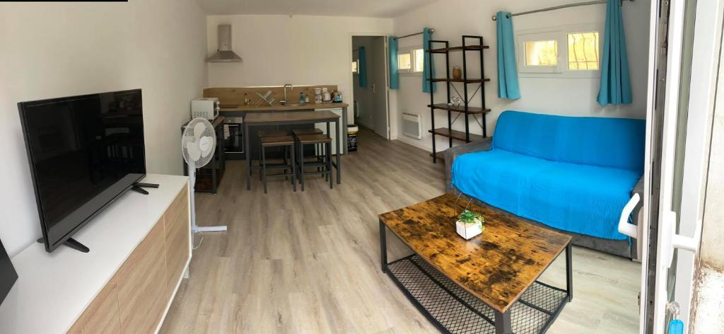 a living room with a blue couch and a table at L'Olivier in Saint-Mitre-les-Remparts