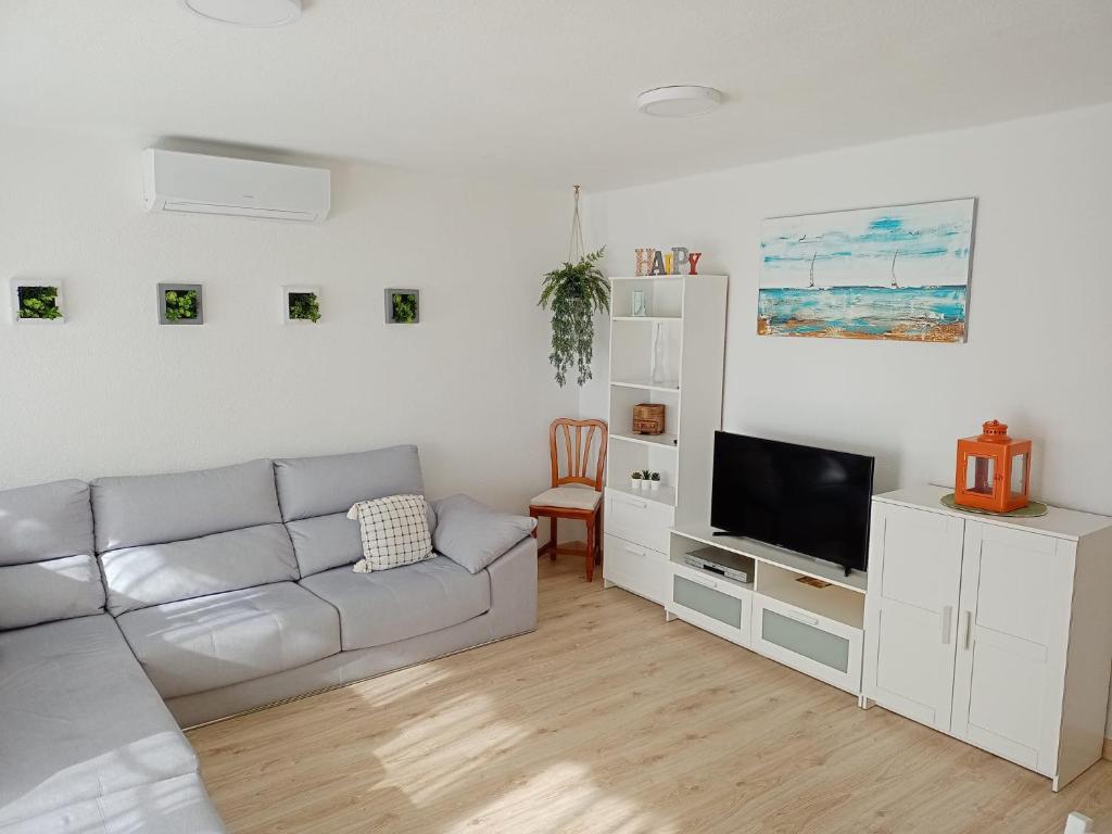 sala de estar blanca con sofá y TV en Apartamento Ciudamar, en Puerto Sagunto