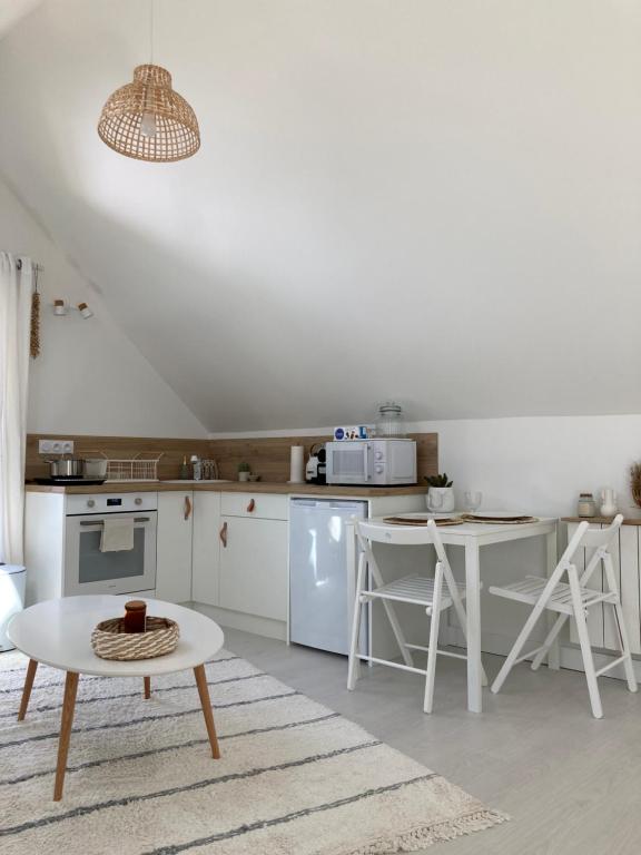 een keuken met witte apparatuur en een tafel en een tafel bij Studio cosy avec coin jardin in Lancieux