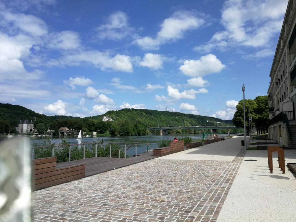 uma passagem junto a um rio com uma ponte em Au fil de la Seine em Vernon