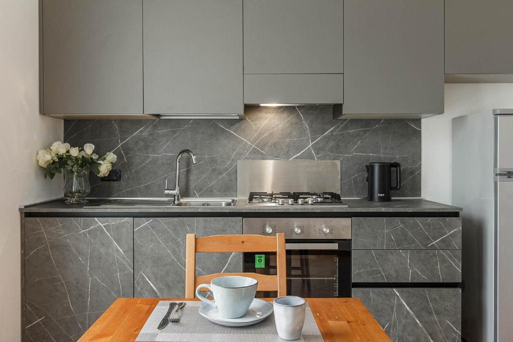 a kitchen with white cabinets and a wooden table at Le Quattro Stelle Villa in Cardano al Campo