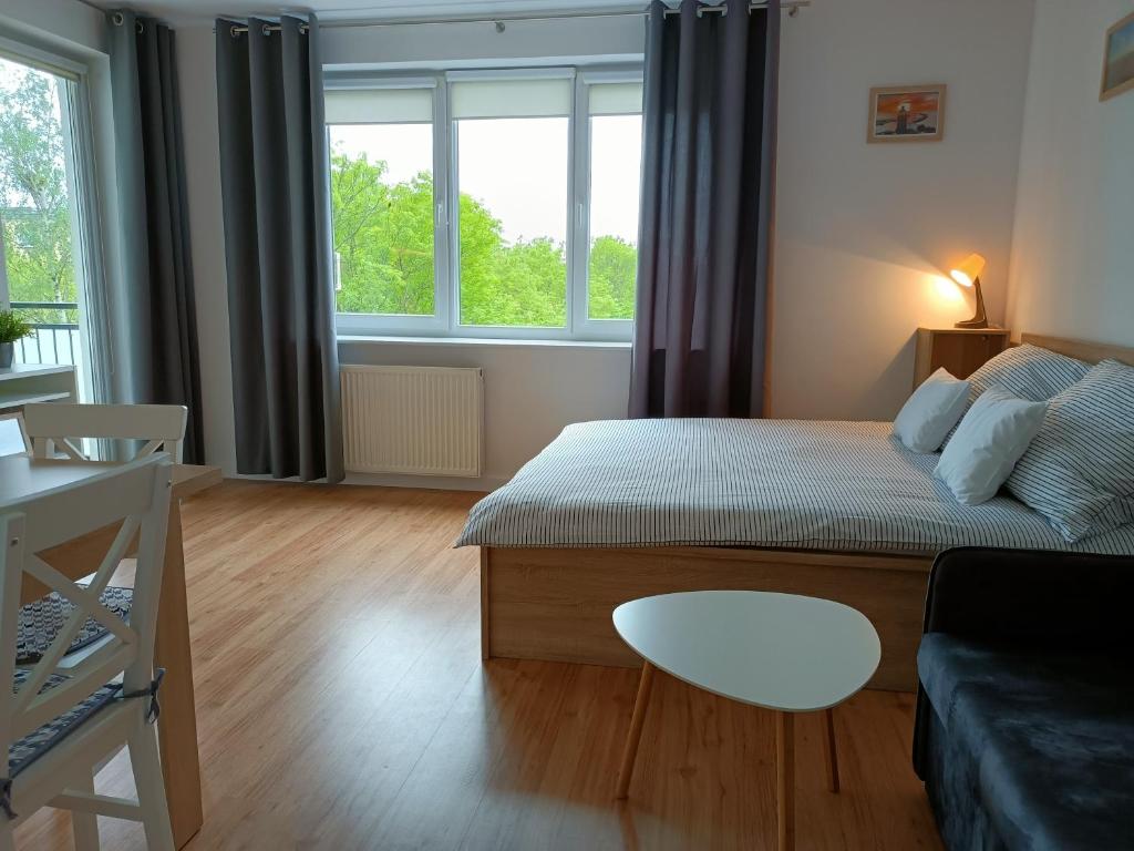 ein Schlafzimmer mit einem Bett, einem Sofa und Fenstern in der Unterkunft Apartament Okopowa 10 Kołobrzeg in Kołobrzeg