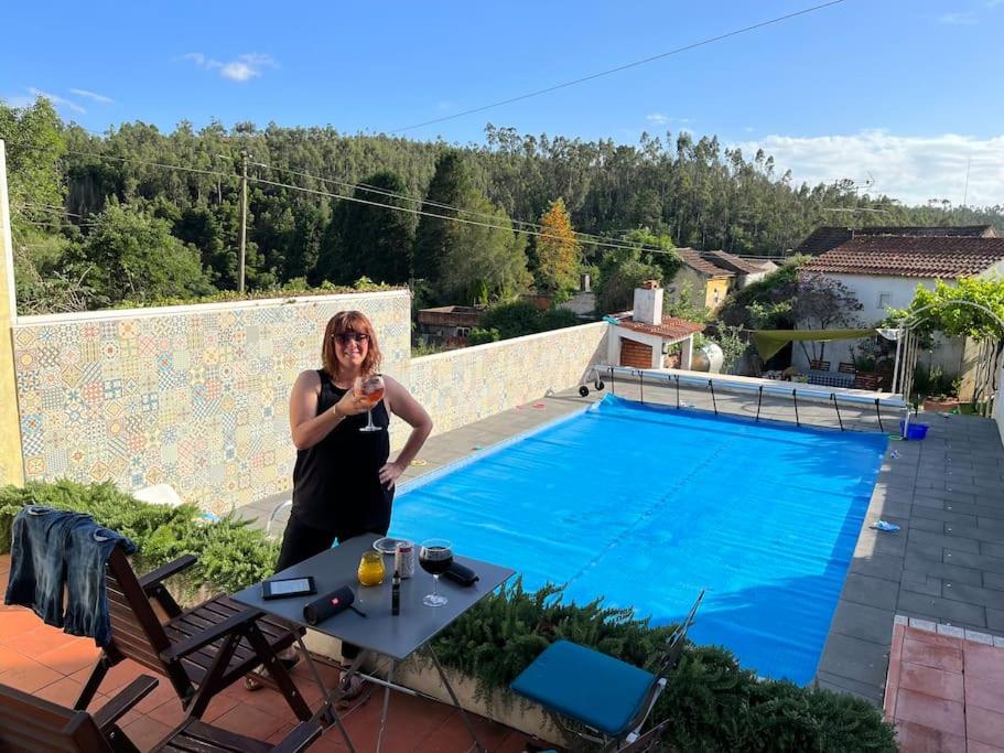 Eine Frau mit einem Glas Wein neben einem Pool. in der Unterkunft Citrus Tree House, private pool and garden. in Angeja