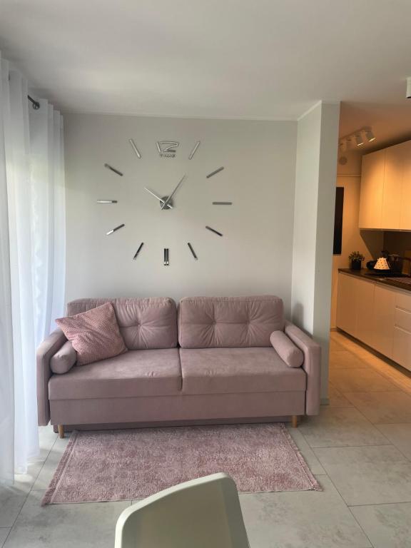 a living room with a couch and a clock on the wall at Apartament Luxor in Niechorze