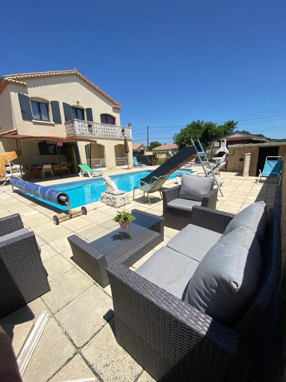 a patio with wicker furniture and a swimming pool at Gite Esprit Etape in Saint-Barthélemy-de-Vals