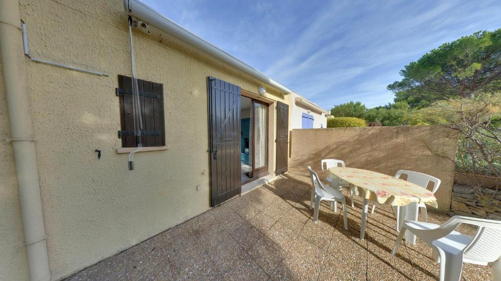 un patio avec une table et des chaises et un bâtiment dans l'établissement Gruissan: Maisonnette T2 avec jardin, à Gruissan