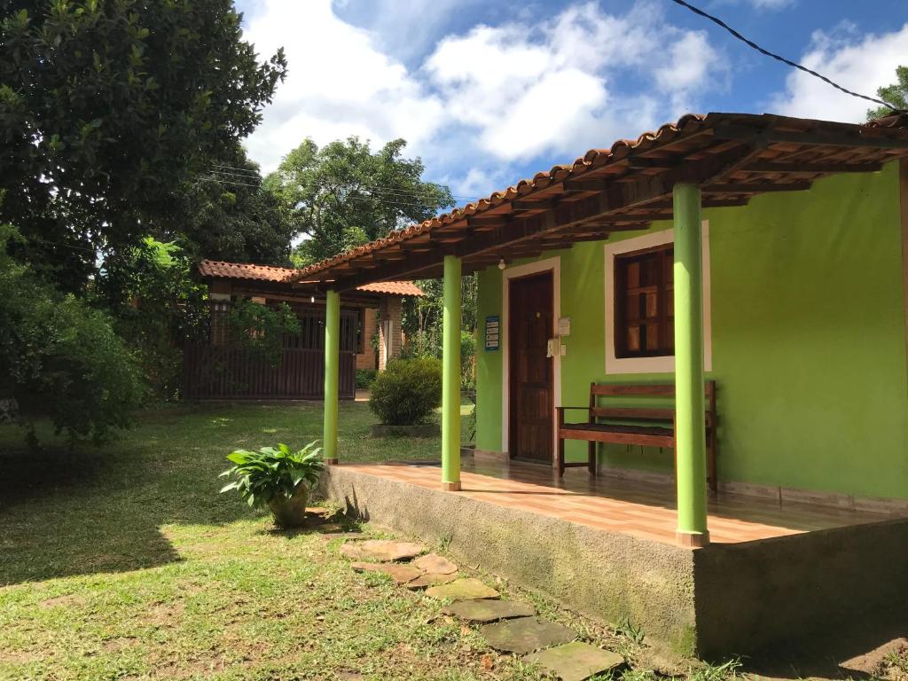 a green house with a bench on a porch at Suite Raio de Sol in Vale do Capao