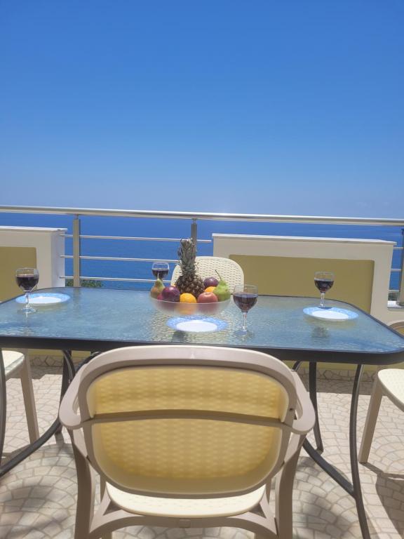 a blue table with two glasses of wine and a bowl of fruit at Villa Thea in Kaloi Limenes