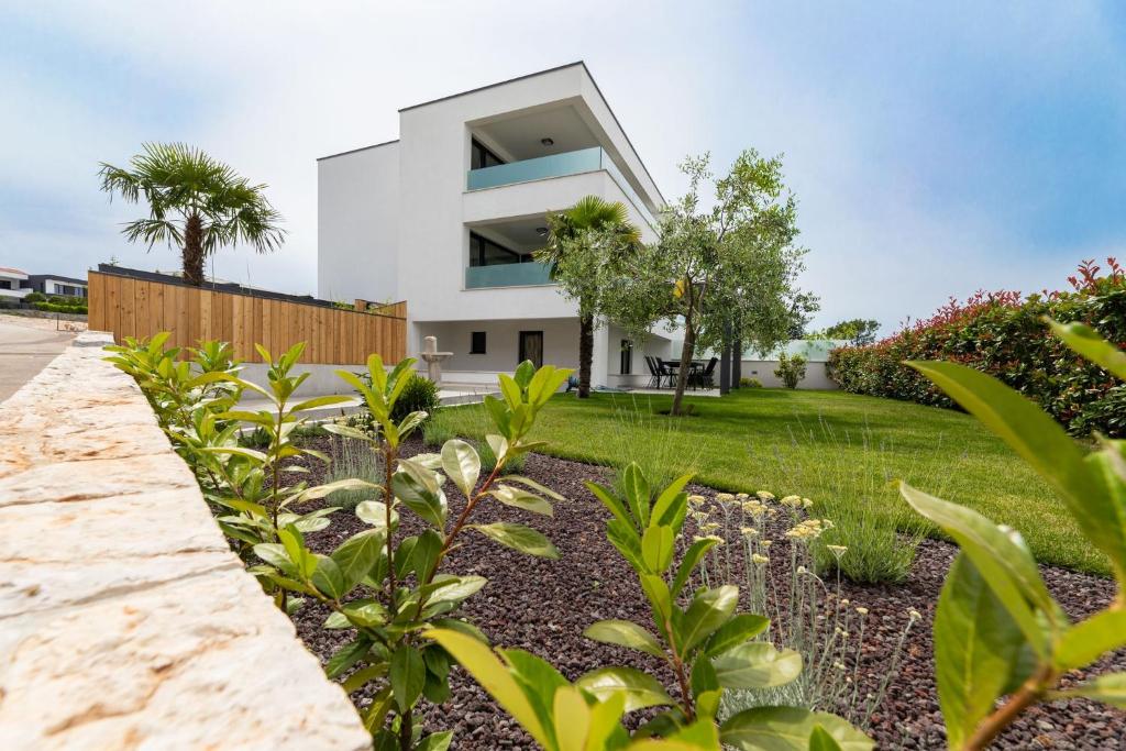 a white house with a yard with plants at Casa Bella Lux in Malinska
