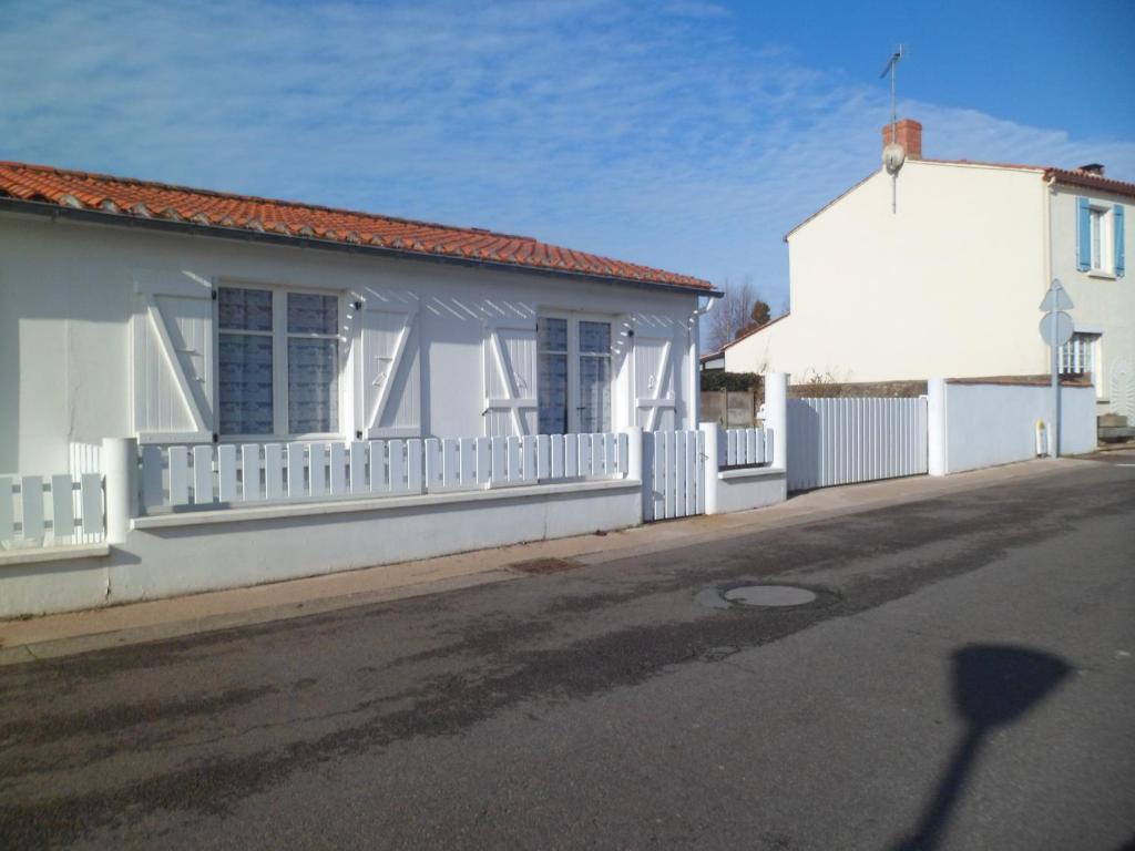 a white building with a white fence next to a street at MAISON DE VACANCES in Saint-Vincent-sur-Jard
