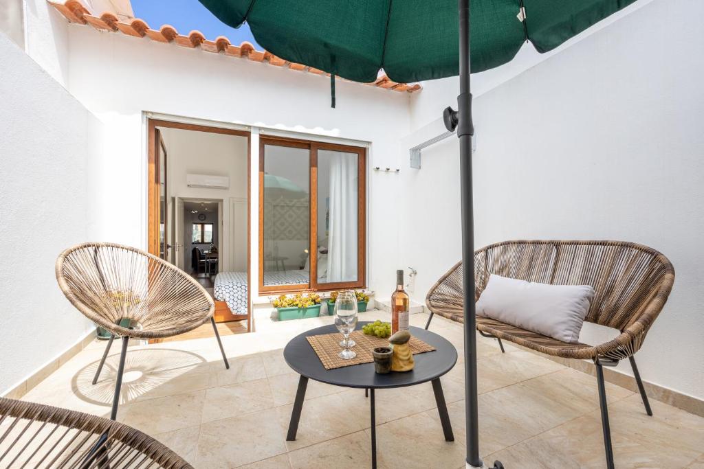 un salon avec deux chaises et un parasol dans l'établissement Casa da Tita Alvor, à Alvor