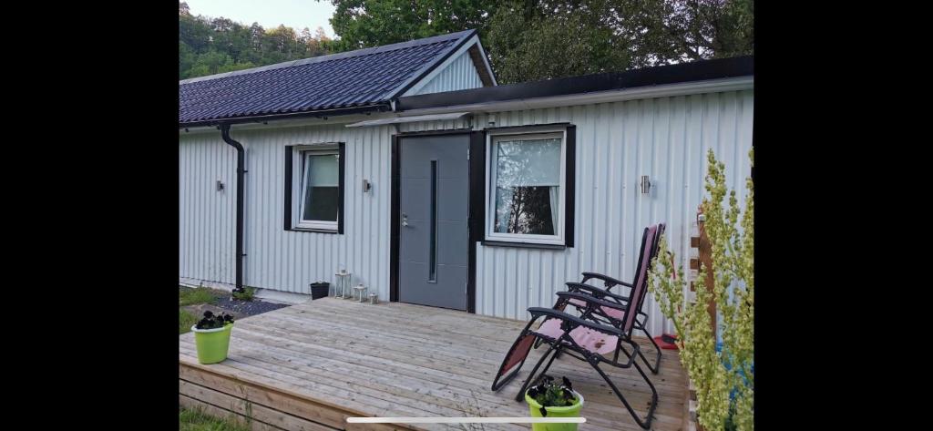 a house with a wooden deck with a bench on it at Stugor Lilleskog in Vargön