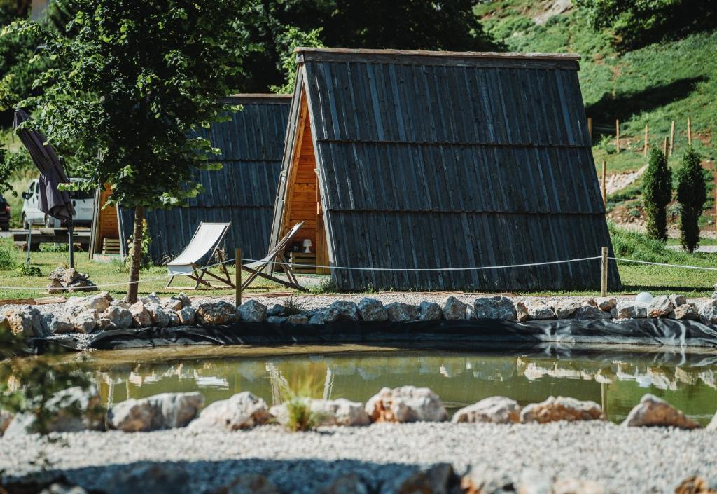 a log cabin with a pond in front of it at Glamping alp hut in camping Garden Park in Radovljica