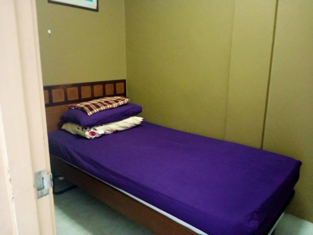Cosy Laketown Service Apartment في Kampong Selemat: سرير في غرفة ذات أغطية ووسائد أرجوانية