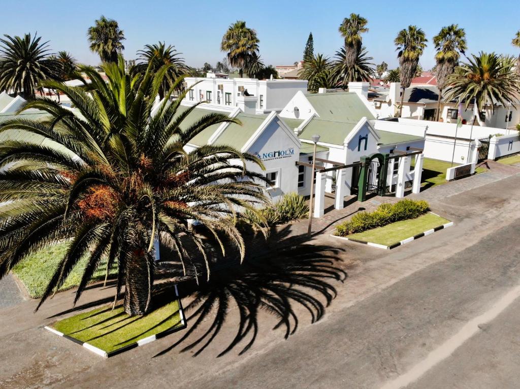 a palm tree in front of a row of white houses at Langholm Hotel in Walvis Bay