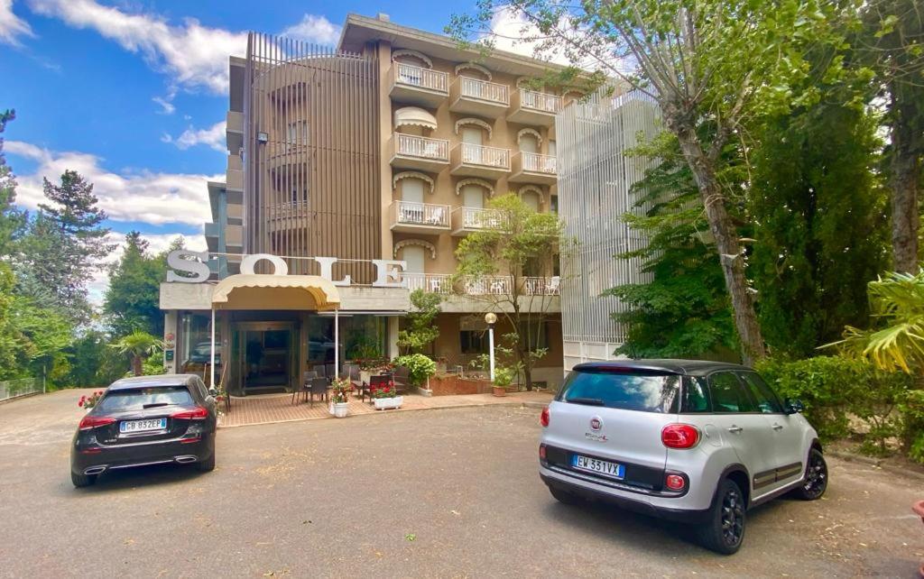 two cars parked in front of a building at Hotel Sole in Chianciano Terme