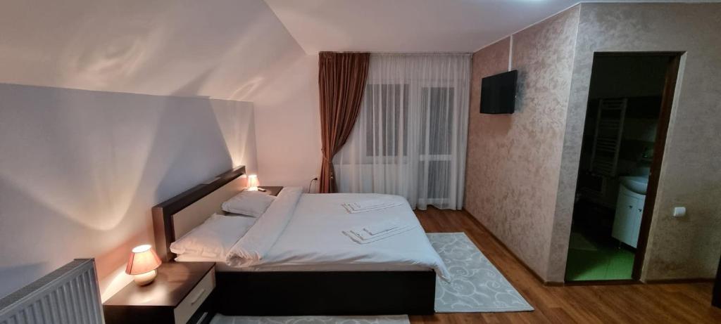 sypialnia z białym łóżkiem i lustrem w obiekcie Pensiunea Vila Maria w mieście Crăcăoani