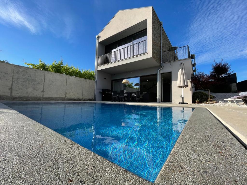 una casa con piscina di fronte a una casa di Casa das Branquinhas - Férias no Minho com piscina! a Ponte de Lima