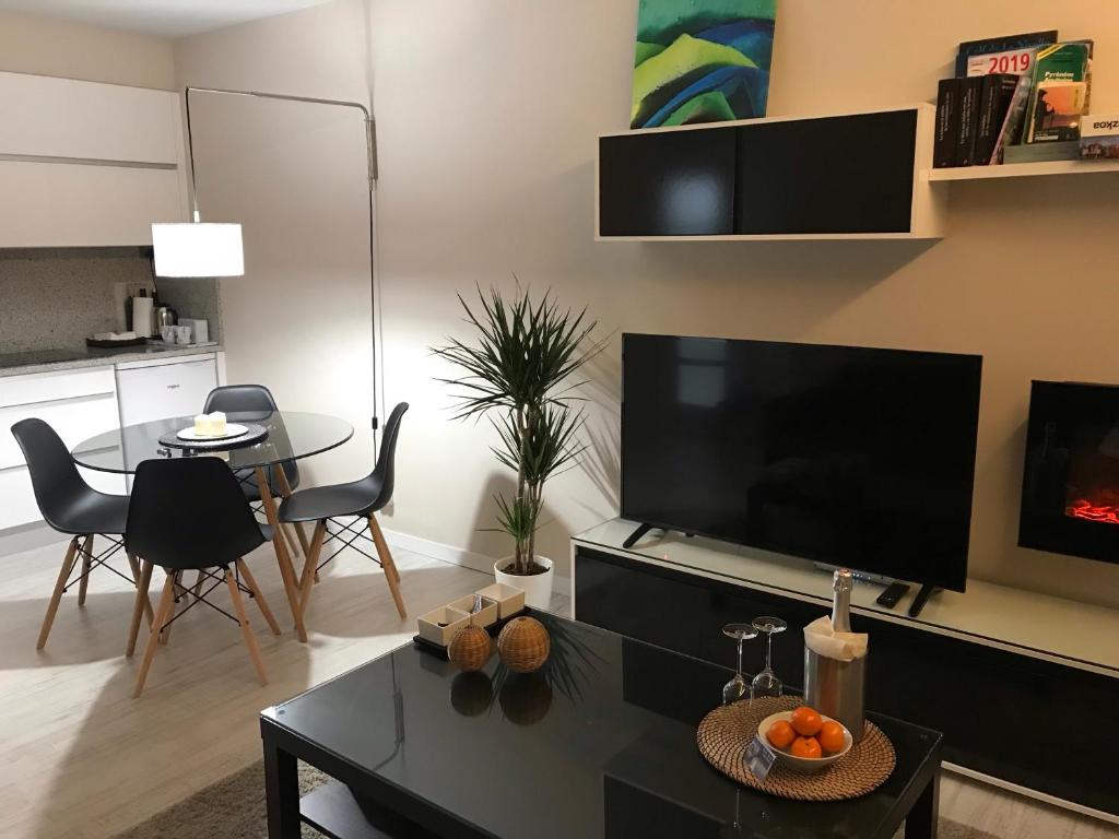 uma sala de estar com uma televisão e uma mesa e cadeiras em Port Bidassoa - T2 Coquet, Parking, Lit XXL, wifi, près de la gare em Hendaye