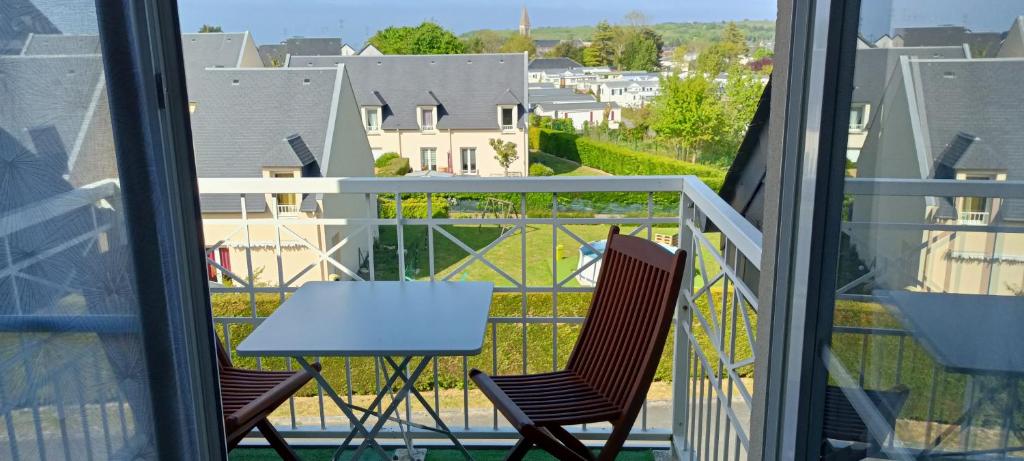 a balcony with a table and chairs and a view of a city at Apt avec belle terrasse vue dégagée séjour lumineux 10 mn à pied centre Port en Bessin proche Bayeux et Omaha Beach in Port-en-Bessin-Huppain