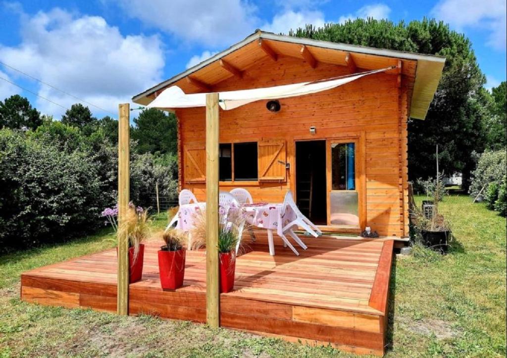 a wooden cabin with a deck in a yard at Cabane Pomme de pin in Le Porge