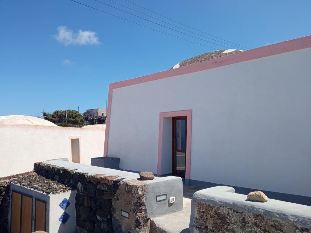 una casa bianca con pareti in pietra e una porta di La casa dei nonni a Pantelleria