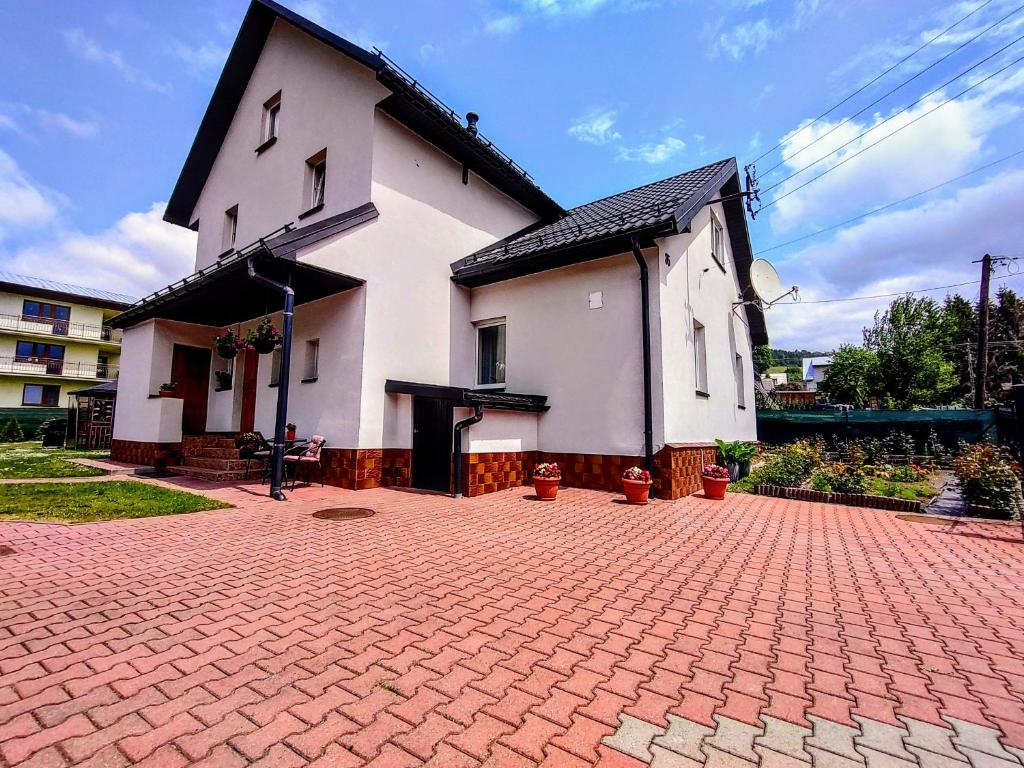 a small white house with a red brick driveway at Apartament nad Strumykiem in Tylicz
