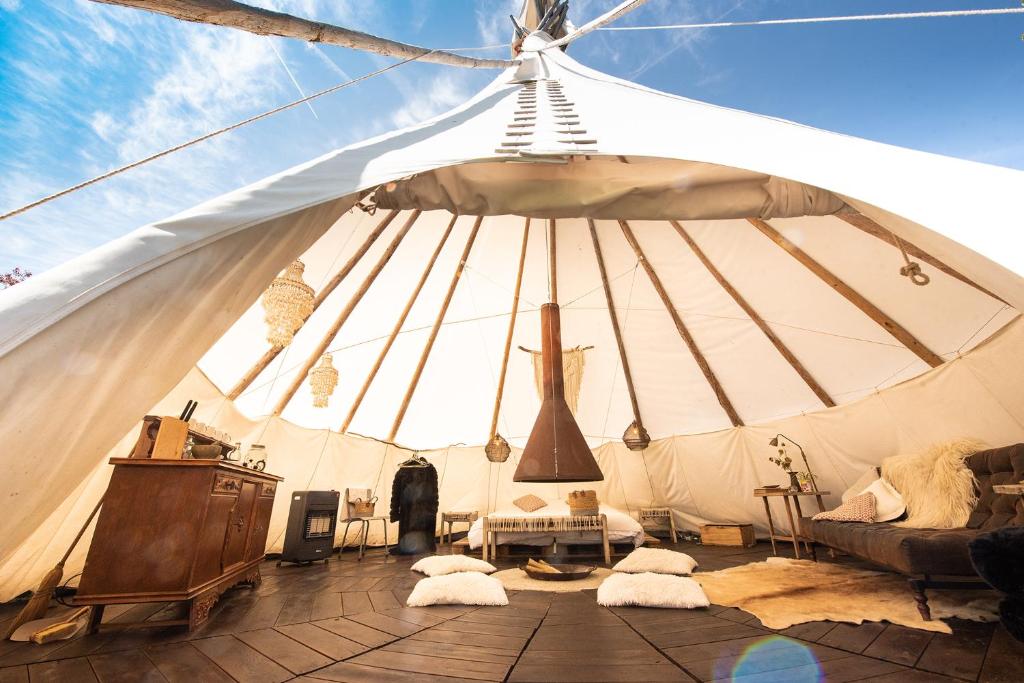 a large white tent with a couch and a table at Slapen tussen de schapen in de Tante Tipi in Zennewijnen