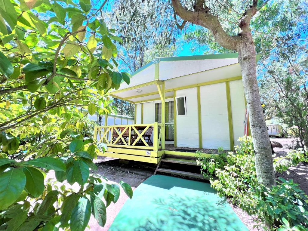 a small yellow and white house in the trees at CAMPING LES ILOTS D'OR in Porto-Vecchio