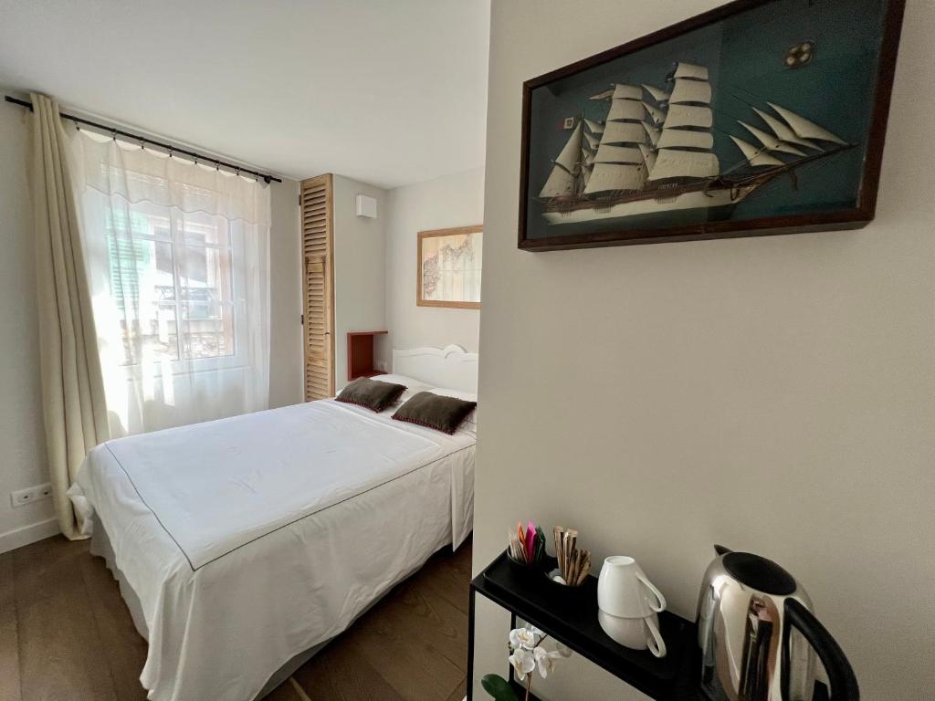 un dormitorio con una cama y una pintura de un barco en la pared en Les Petits Volets 2, en Antibes