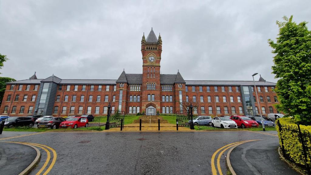 um grande edifício de tijolos vermelhos com uma torre de relógio em Birch Hill Clock Tower em Rochdale